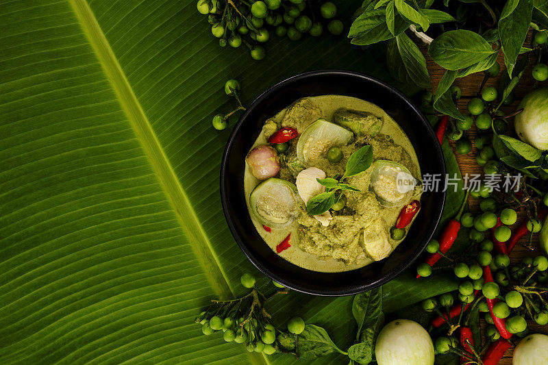 国际知名的泰国绿椰子咖喱'Gaeng Keow Wan Gai'，与鸡肉，在碗中，周围的材料，在香蕉叶的背景。